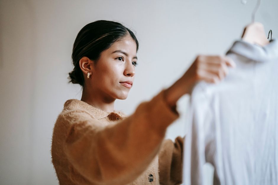 Focused female with dark hair in casual outfit selecting garments while working in modern boutique