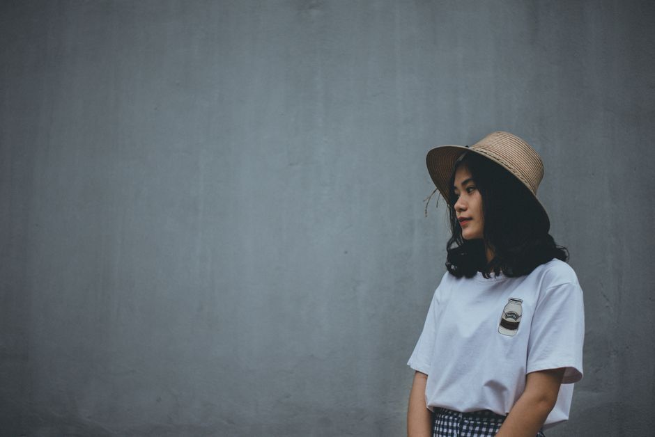 Side view of a young woman in vintage fashion with a hat, outdoors.