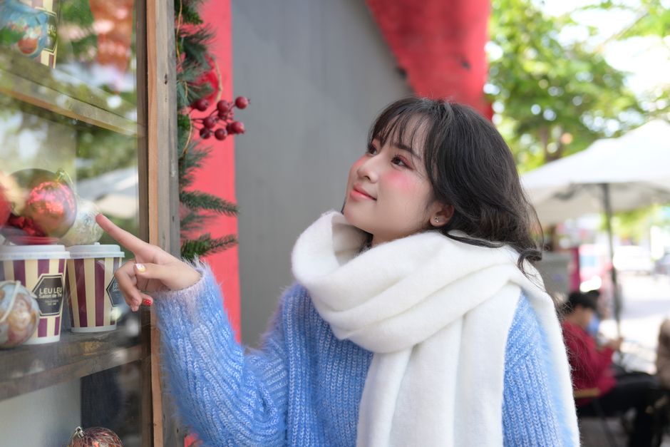 Smiling woman in winter clothes admiring festive decorations outdoors.