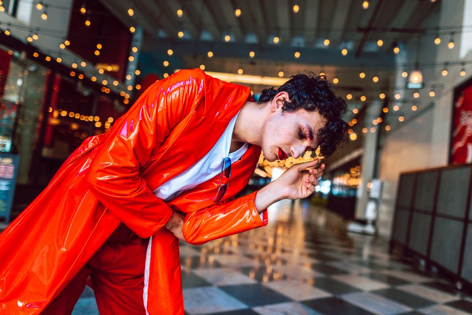 Expressive street portrait with eye-catching red outfit under string lights.