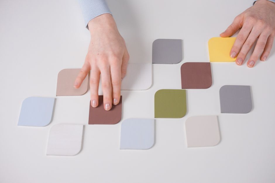 Artistic arrangement of colorful swatches by hands on a minimal white table.
