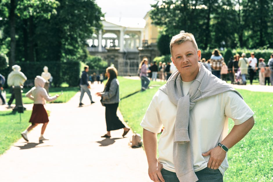 Man in park with people, historic architecture, summer, social vibe.