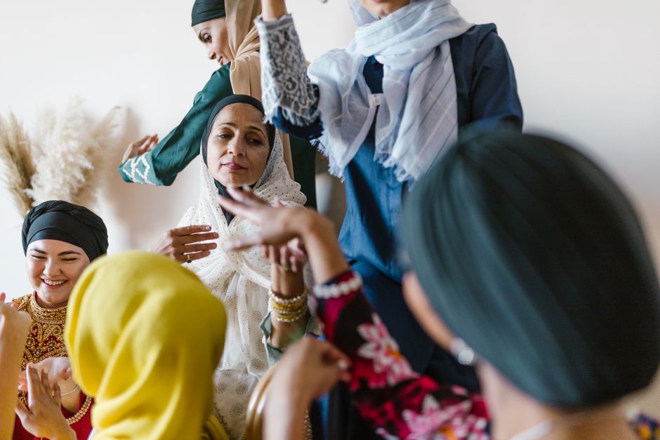 Group of diverse Muslim women in colorful attire celebrating and enjoying each other's company.