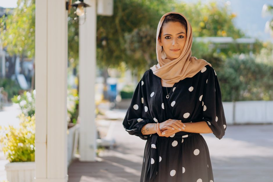 Portrait of a woman in a hijab wearing a polka dot dress outdoors with a serene expression.