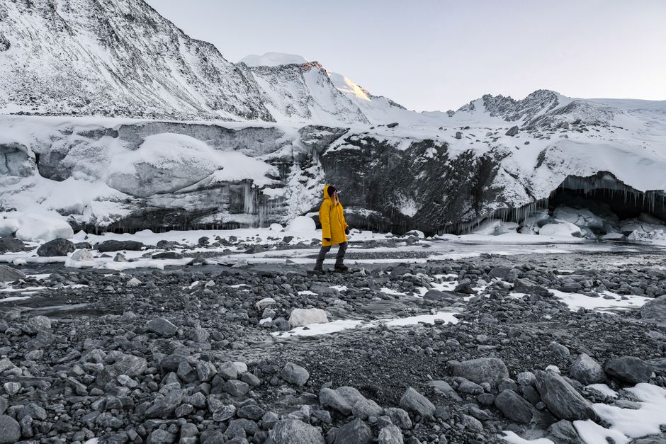 A person in a yellow jacket exploring the snowy landscape of Bayan-Ölgii, Mongolia during winter.